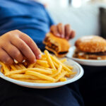 Overweight teenage boy eating too much fried food