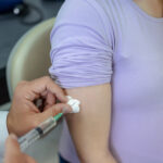 A pregnant young woman receives a vaccine at a preventive examination by a doctor