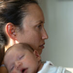 A sad mother sitting at home suffering from postpartum depression. Motherhood problems.