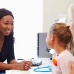 Mother And Daughter Visiting Doctor In Surgery