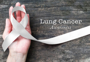 Lung cancer awareness month with white/ light pearl color ribbon on woman's hand support on aged wood