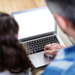 Rear view of father and daughter using laptop