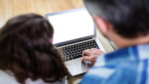 Rear view of father and daughter using laptop