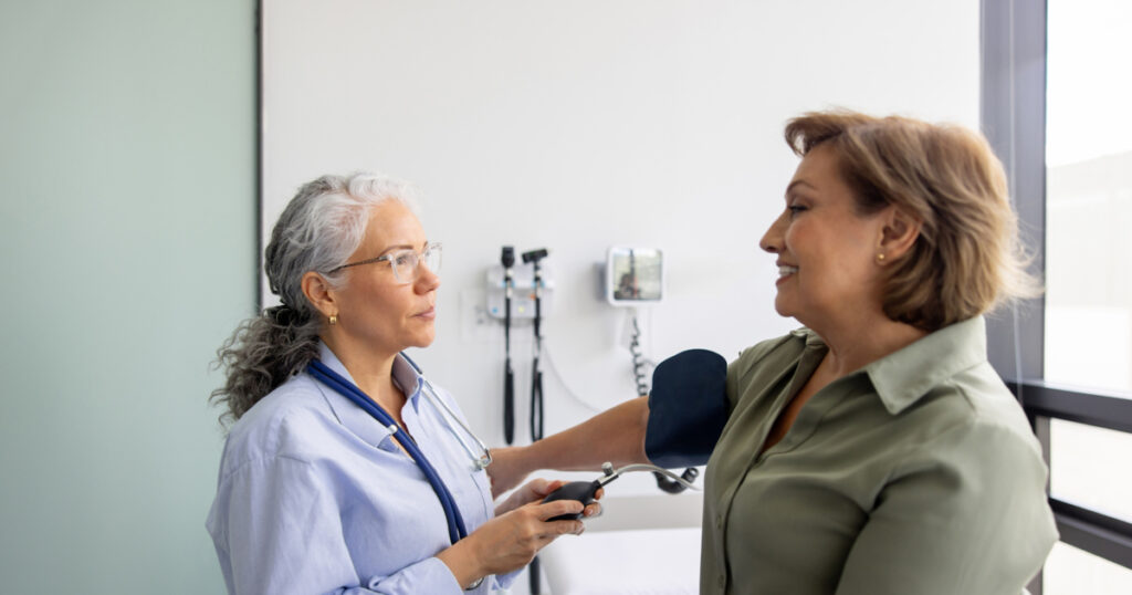 Doctor checking the blood pressure on a woman in the examination room