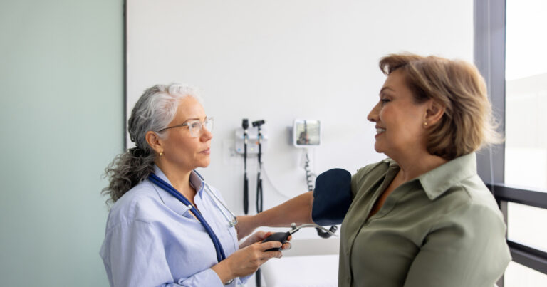 Doctor checking the blood pressure on a woman in the examination room