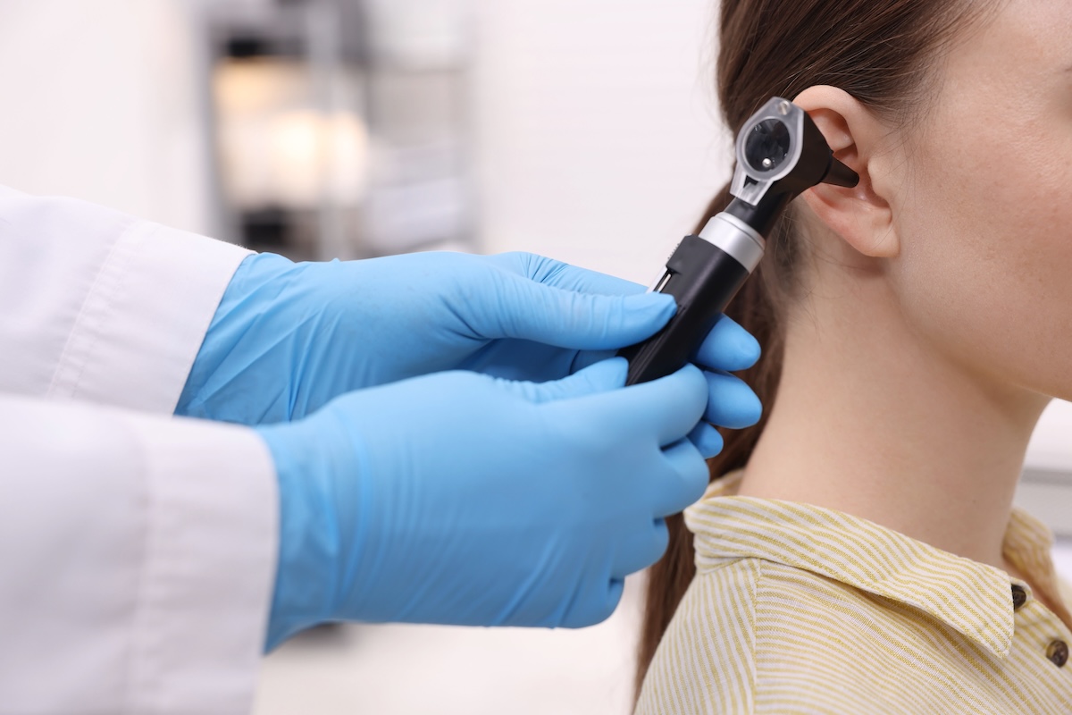 Hearing test. Doctor examining patient’s ear with otoscope in clinic, closeup